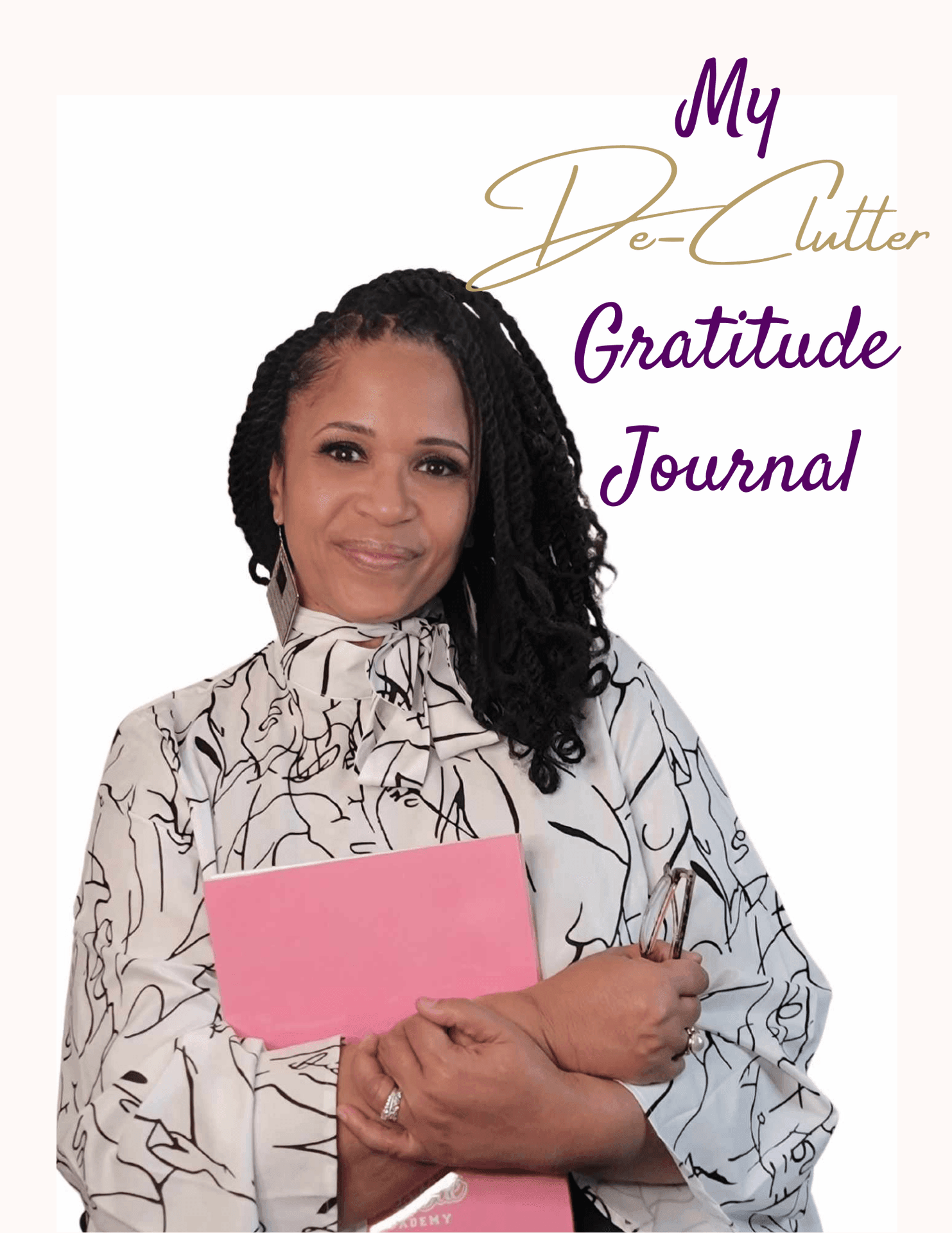 Person holding a pink book titled 'My De-Clutter Gratitude Journal' wearing a patterned blouse.